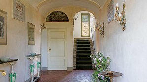 Un couloir avec une porte blanche, un escalier et un luminaire fixé au mur.