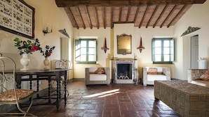 Un salon traditionnel avec une cheminée, deux canapés, une table à manger avec des chaises et une grande fenêtre.