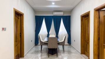 A hotel room with a dining area featuring a table and chairs, a ceiling light, and an air conditioning unit.