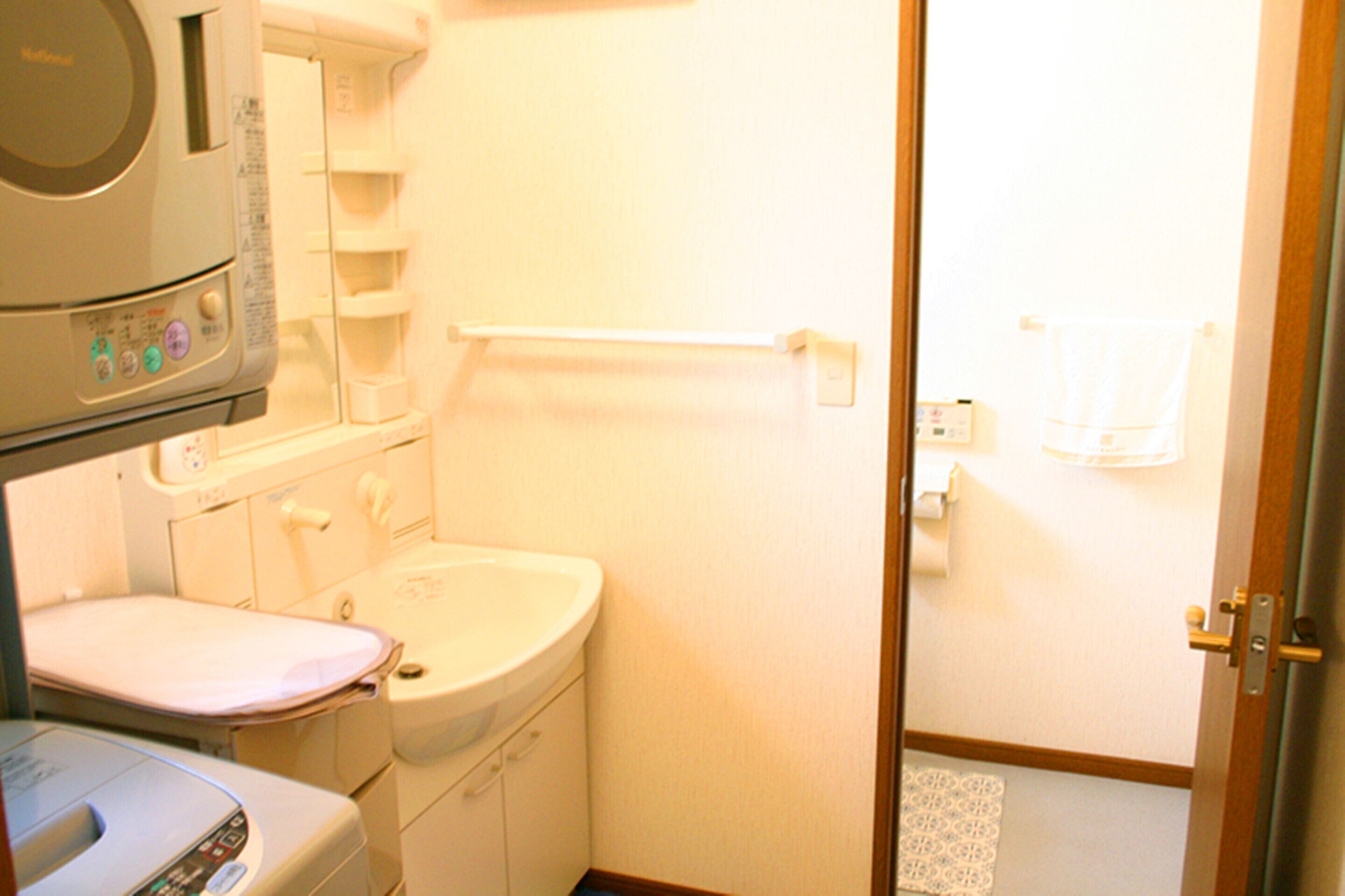 Een kleine badkamer met toilet, wastafel en een magnetron boven de wastafel.