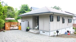 A single-story house with a covered porch, a small outdoor seating area, and a gravel driveway. - Lake Yamanaka Resort House II (Yamanakako)