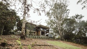 A modern house with a large deck, surrounded by trees and a grassy area. - Wallaby 2 Bed, 1 Bath Cottage - Private Parkland Setting with Lake View (North Maleny)