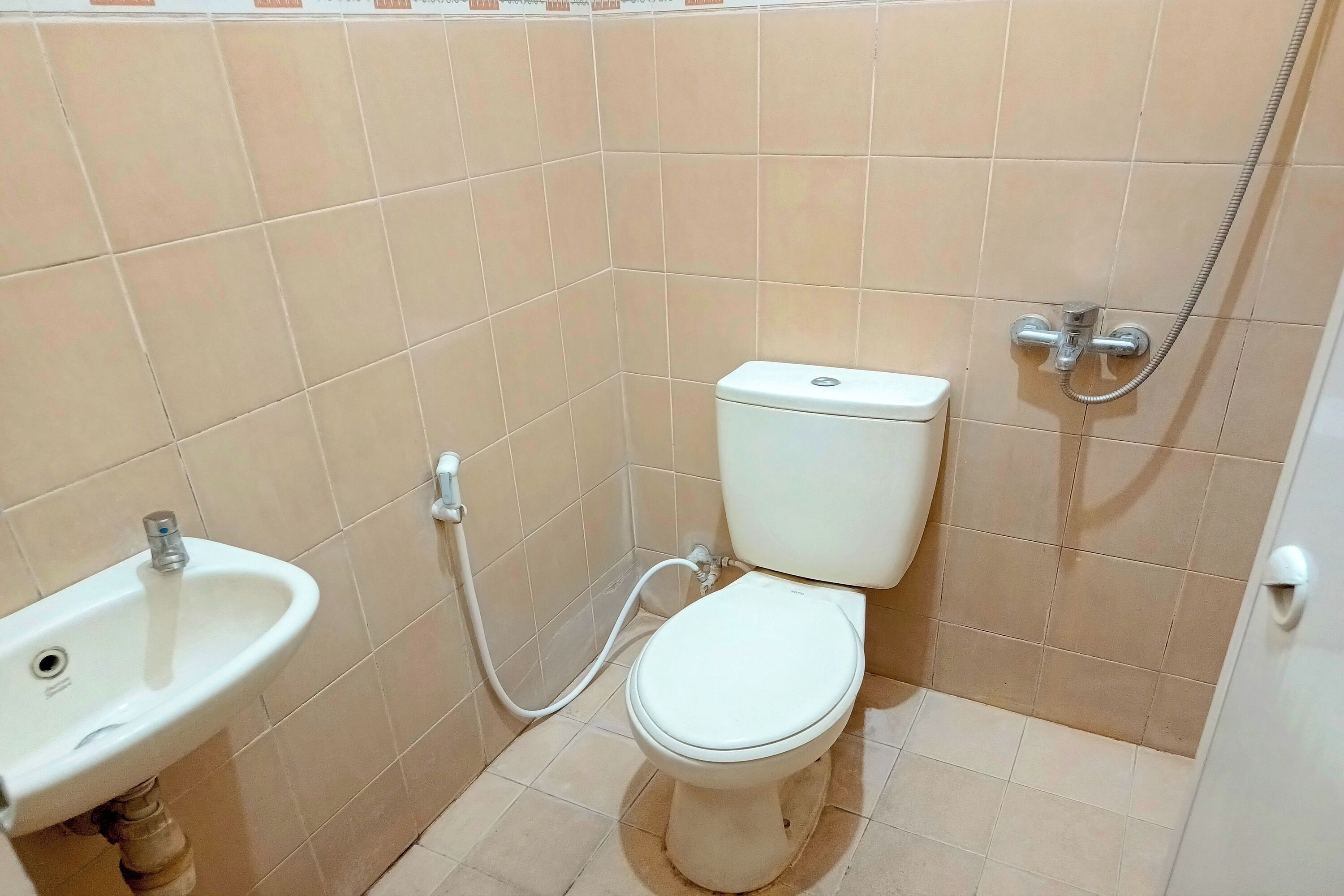 Et lille badeværelse med toilet, håndvask og brusebad.