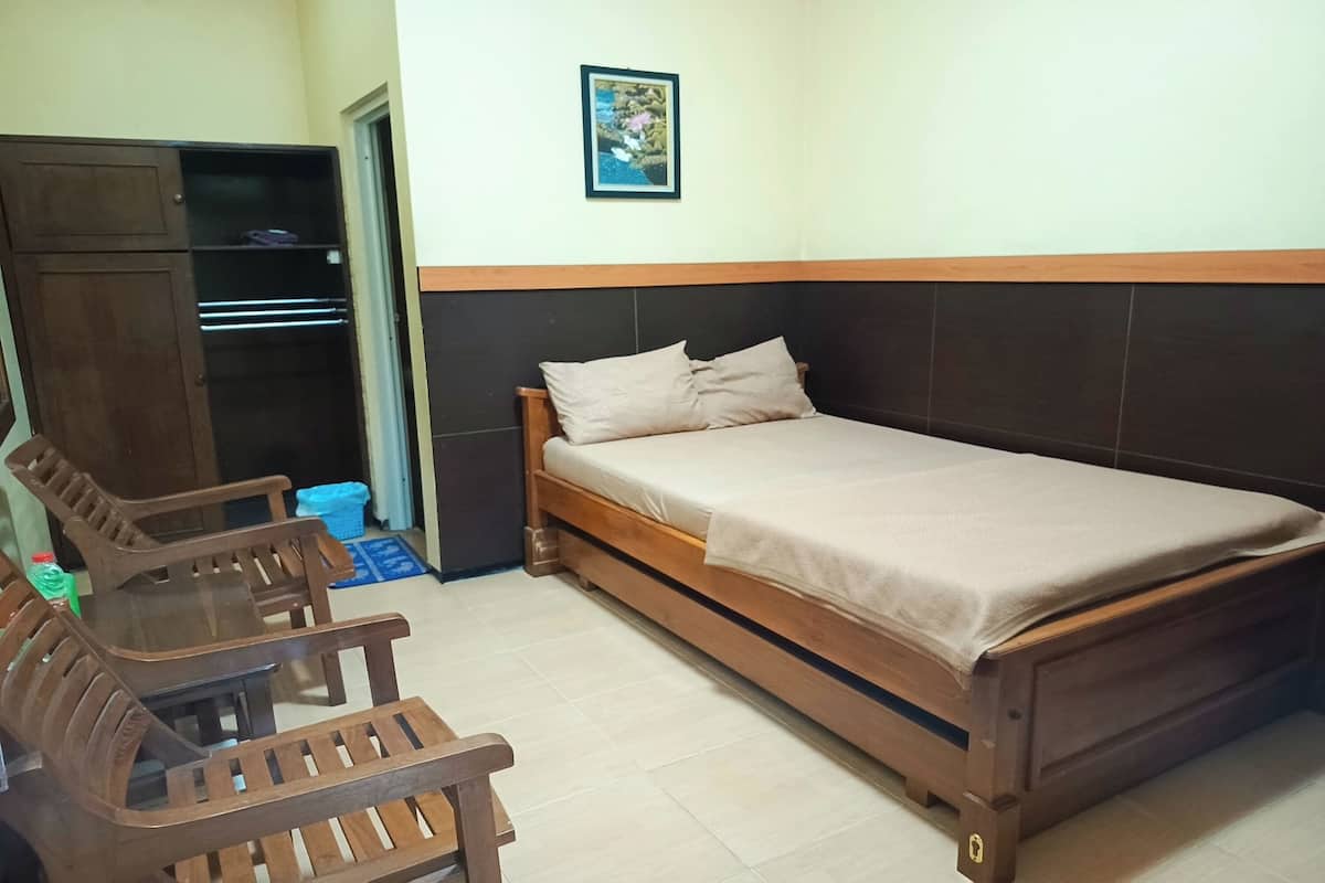 A single bed with a wooden frame and headboard, a wooden table with chairs, and a wardrobe.