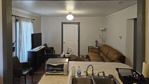Ein kompakter Wohnraum mit einer Küchenzeile, einem Essbereich und einer Sitzecke mit Sofa.