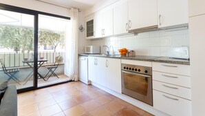 Una cocina moderna con armarios blancos, un horno de acero inoxidable y un microondas. Hay una zona de comedor con una mesa y sillas afuera.