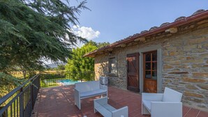 A stone building with a tiled patio, outdoor furniture, and a view of a swimming pool. - Beautiful private villa with private pool, WIFI, terrace, pets allowed and panoramic view (Cortona)