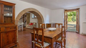A dining area with a wooden table and chairs, a cabinet with glass doors, and an arched brick structure. - Beautiful private villa with private pool, WIFI, terrace, pets allowed and panoramic view (Cortona)