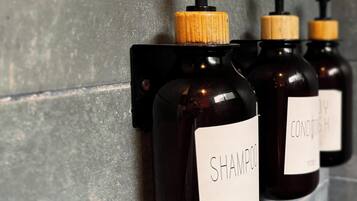 Tres botellas de champú y acondicionador sujetas a una pared.