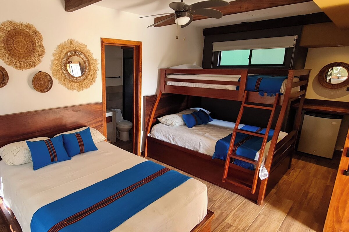 A room with a bunk bed, a single bed, and a ceiling fan.