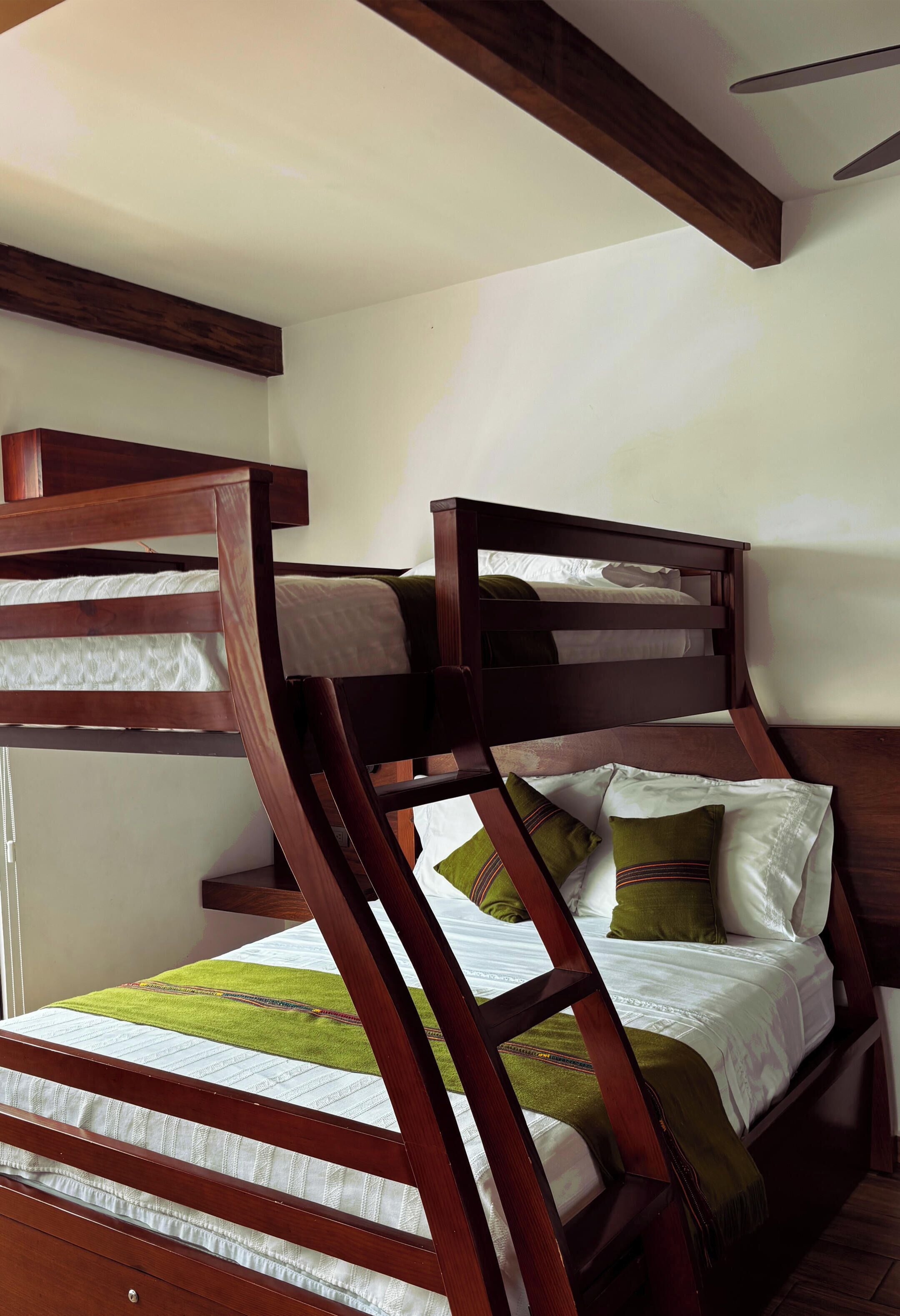 A bunk bed with a wooden frame and white bedding.