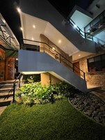 Un edificio moderno de varios niveles con escaleras, jardín exterior y detalles de piedra.