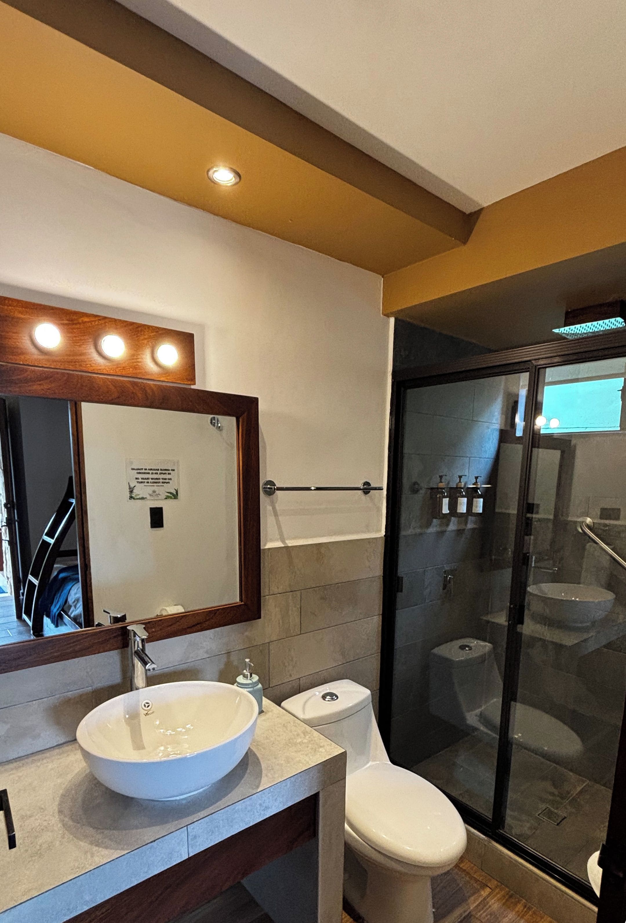 Un bagno moderno con un lavandino ampio, il water e un box doccia in vetro.