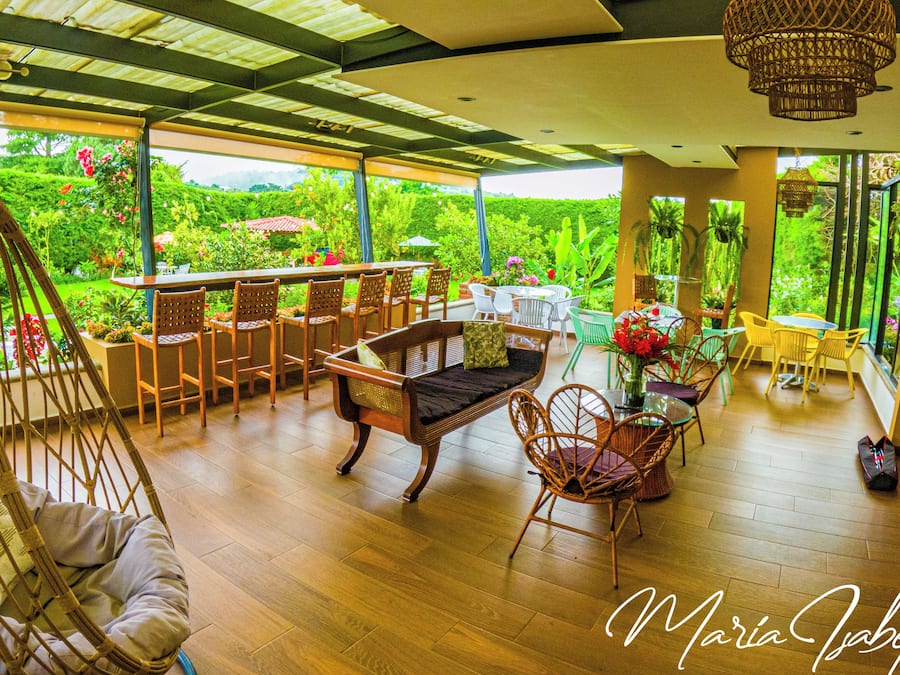 A spacious outdoor area with a wooden floor, wicker furniture, and a hanging chair.