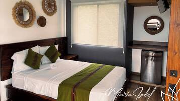 A neatly made bed with a green throw, a wooden headboard, and two decorative wall mirrors.