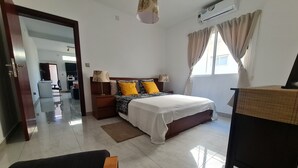 Ein Schlafzimmer mit einem Bett, Nachttischen, einer Lampe, einem Schreibtisch und einem Stuhl.