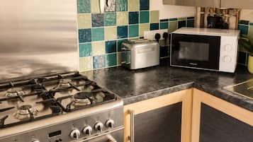A kitchen with a gas stove, a toaster, a microwave, and wooden cabinets.