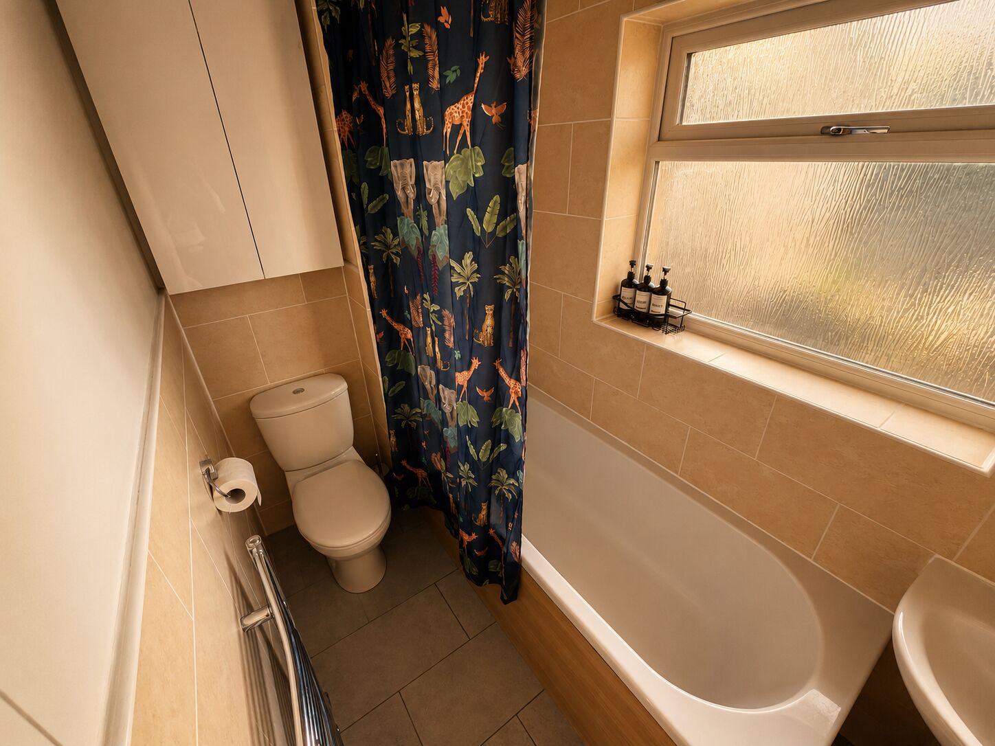 A bathroom with a toilet, bathtub, and a window with a frosted glass view.