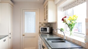 A kitchen with a double sink, a microwave, and a window with a view. - Haven 3 Bedroom House in Whalley (Clitheroe)