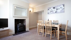 A dining area with a fireplace, a television, and a painting on the wall. - Haven 3 Bedroom House in Whalley (Clitheroe)