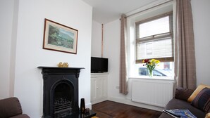 A living room with a fireplace, a television, a sofa, and a window with curtains. - Haven 3 Bedroom House in Whalley (Clitheroe)
