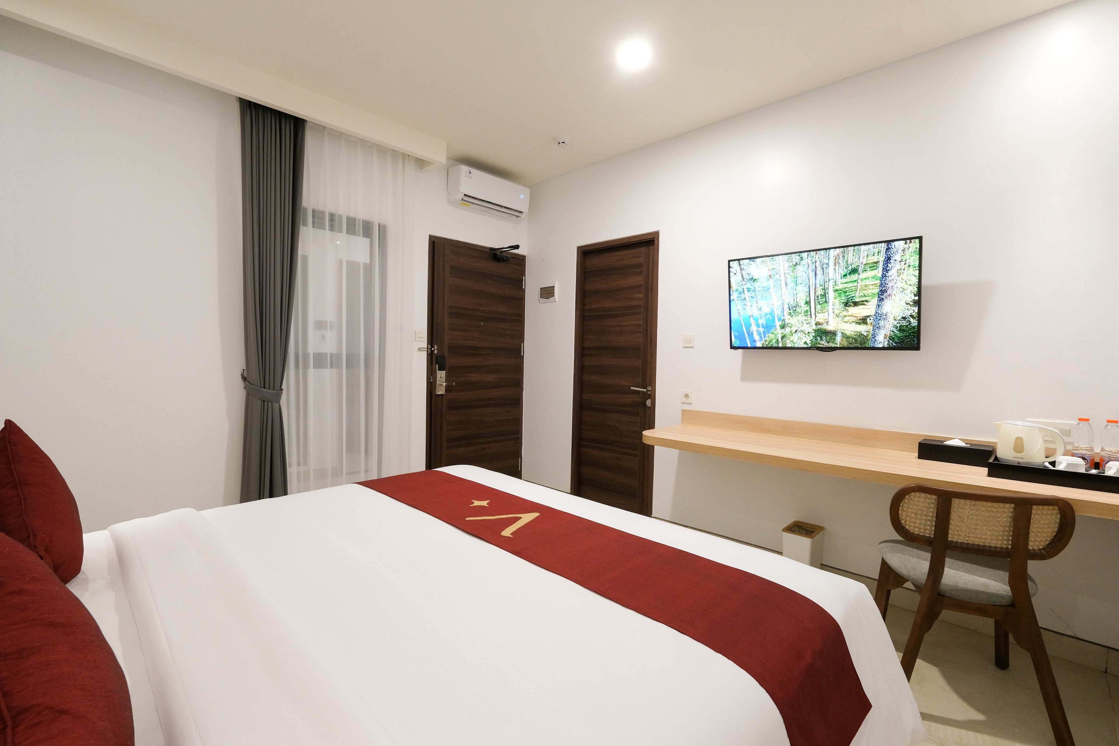A hotel room with a bed, a desk, a chair, a television, and a window with curtains.