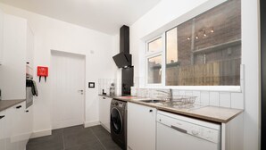 A modern kitchen with a washing machine, dishwasher, and a window with a view of the outside.