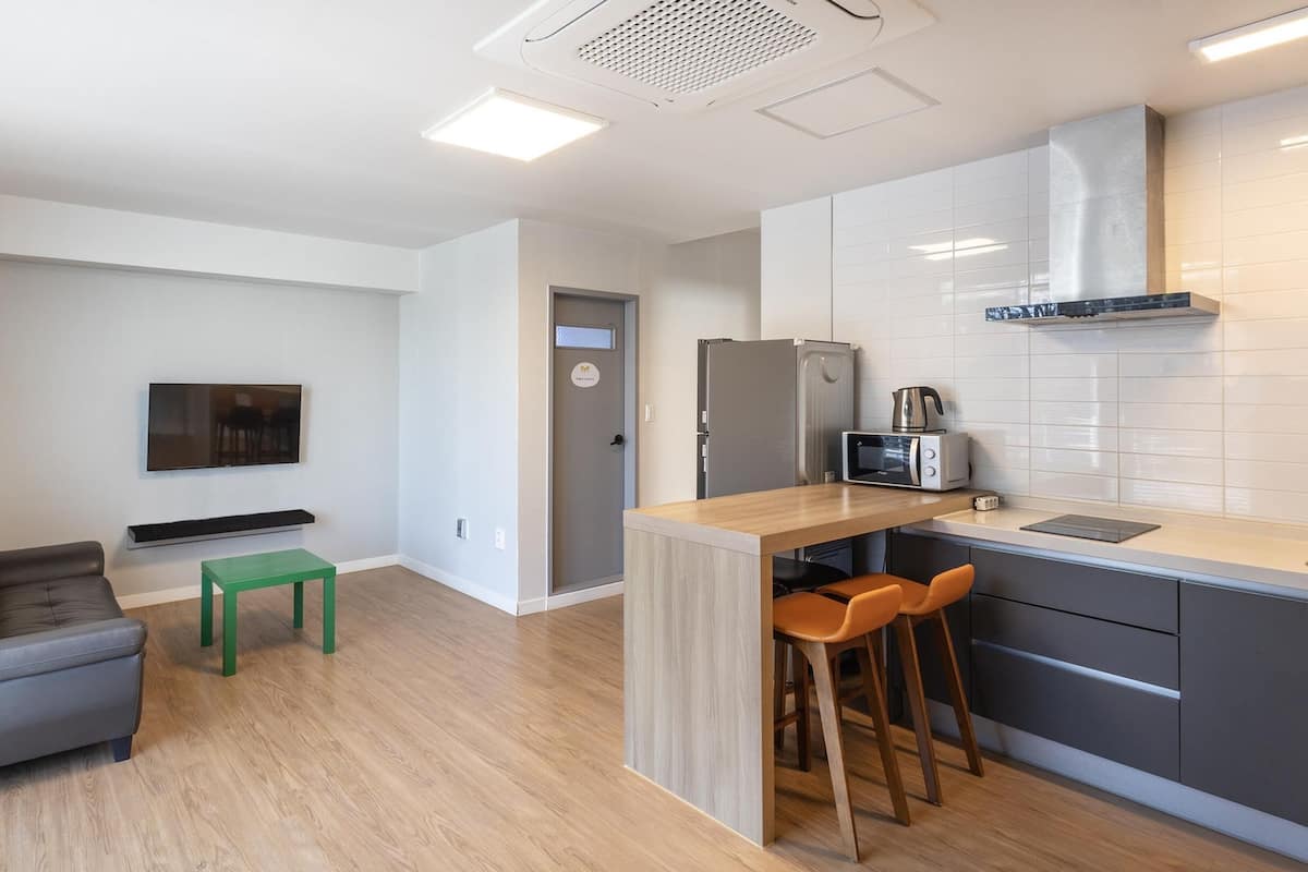 Eine moderne Küche mit integriertem Mikrowellenherd, Kühlschrank und Kaffeemaschine. Ein kleiner Essbereich mit Tisch und Stühlen vorhanden.