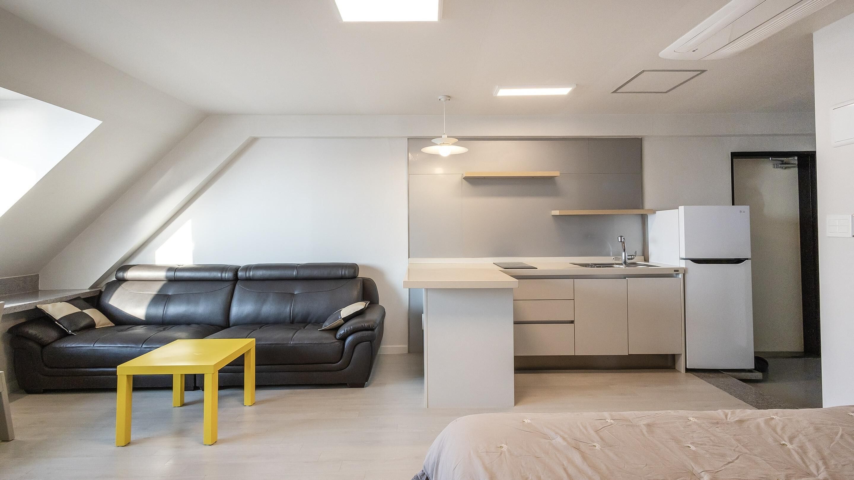 Un espace de vie compact comprenant un coin cuisine, un canapé, une petite table et un lit.
