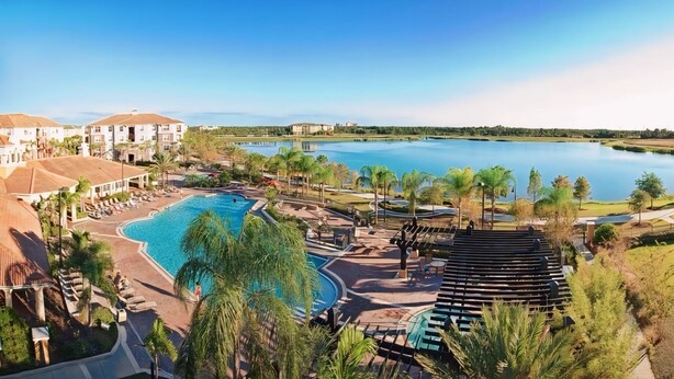 Un resort con una gran piscina, un campo de golf y vistas a un lago.