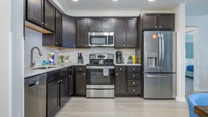 Una cocina moderna con armarios de madera oscura, electrodomésticos de acero inoxidable y encimera de color claro.