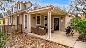 Une maison à deux étages dotée d’un porche abrité, d’un coin repas avec mobilier d’extérieur et d’un barbecue.