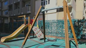 Un parque infantil con tobogán, columpios y una estructura para escalar.