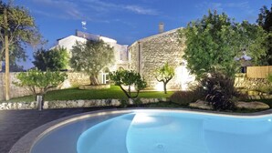 A swimming pool with a stone wall and trees in the background. - Villa Pruno, Scicli, Italy (Scicli)