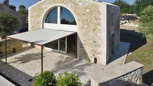 A stone building with a large arched window, a covered patio, and a stone wall. - Villa Pruno, Scicli, Italy (Scicli)