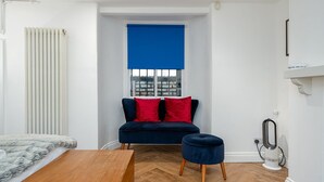 A compact room with a sofa, ottoman, and a bed.