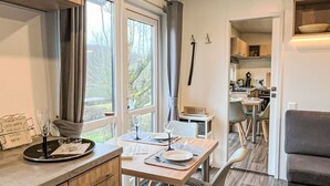 Ett modernt kök med matplats, stora fönster och en mysig sittgrupp.