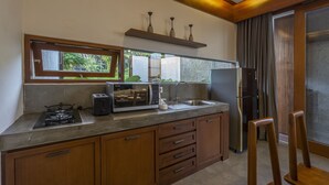 Eine moderne Küche mit Gasherd, Toaster und Kühlschrank. Ein Fenster bietet Blick ins Grüne.