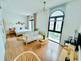 Una habitación de hotel moderna con una cama grande, un sofá, una mesita de centro y un televisor.