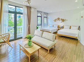Una habitación de hotel moderna con dos camas, un sofá, una mesa de madera y un balcón con cortinas.