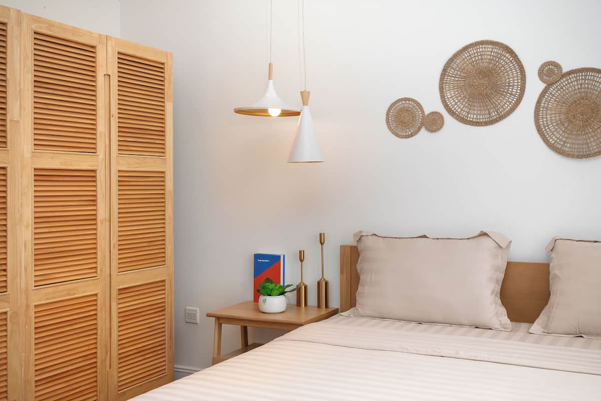 A bedroom with a bed, bedside table, lamp, and wall decorations.