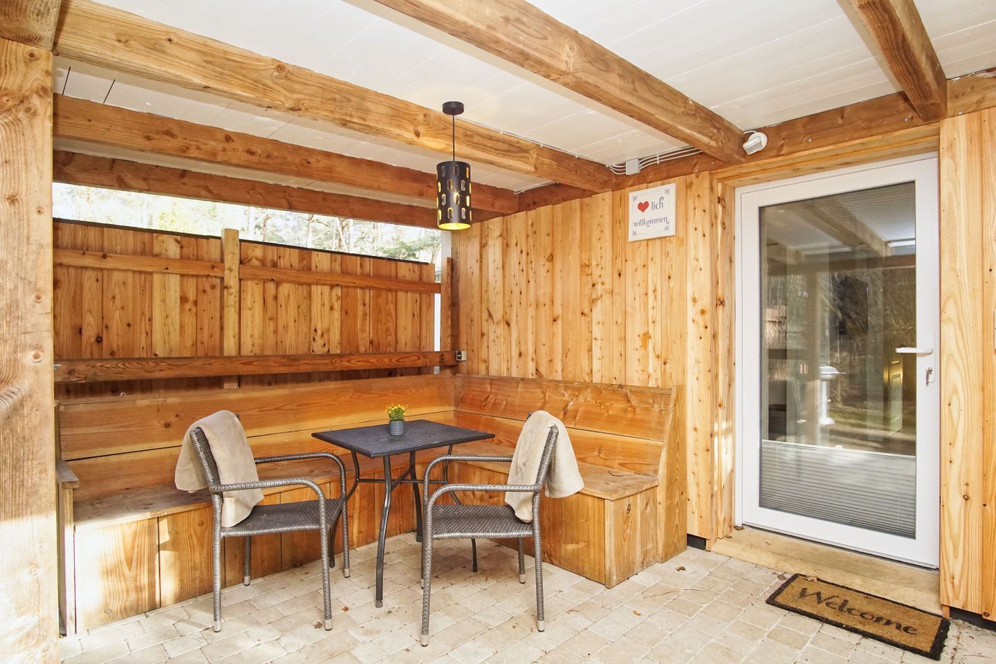 Uma cabana de madeira com um banco, uma mesa e duas cadeiras.