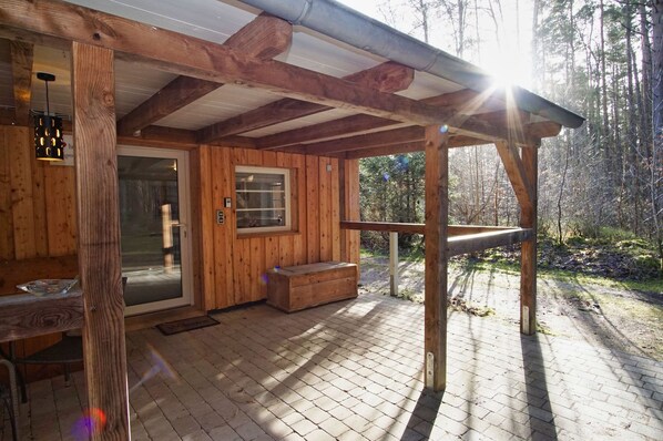 A wooden cabin with a covered porch, a glass door, and a bench.