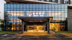 A modern hotel entrance with a glass facade and a sign reading "Mansion Hotel."