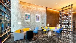 A modern lobby with a marble floor, colorful sofas, and a large bookshelf.