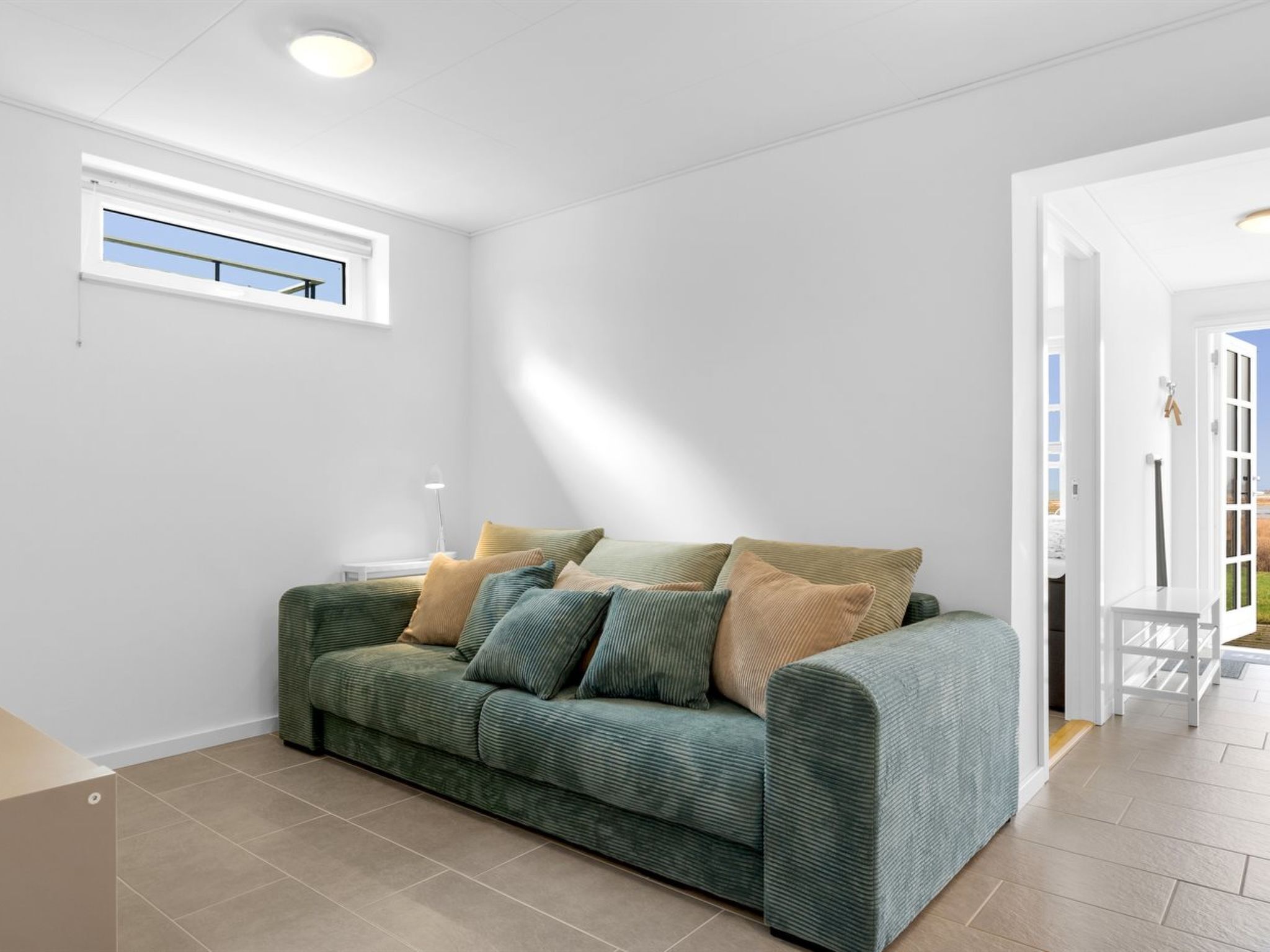 Ein modernes Wohnzimmer mit einem grünen Sofa, einem kleinen Tisch und einem Fenster mit Blick.
