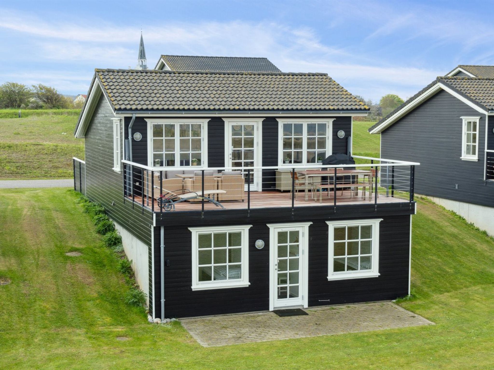 A two-story house with a balcony, large windows, and a tiled roof.