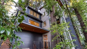 A modern two-story house with a wooden deck, surrounded by tall trees. - Secluded Downtown Modern Lux Retreat in Redwoods (Mill Valley)