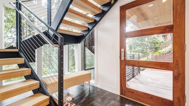 A modern staircase with wooden steps and metal railings, leading to a wooden door with glass panels. - Secluded Downtown Modern Lux Retreat in Redwoods (Mill Valley)