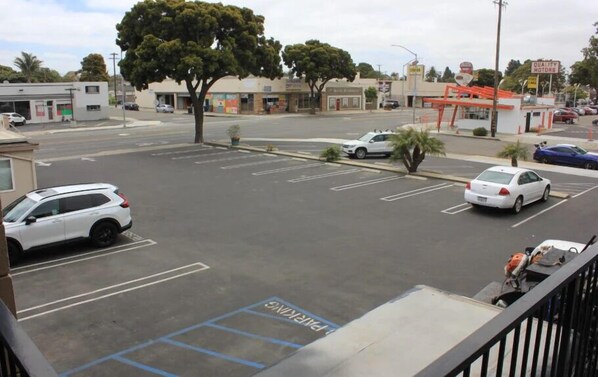 Un estacionamiento con espacios delimitados, un coche blanco y un edificio con un cartel que dice "Quality Motors".
